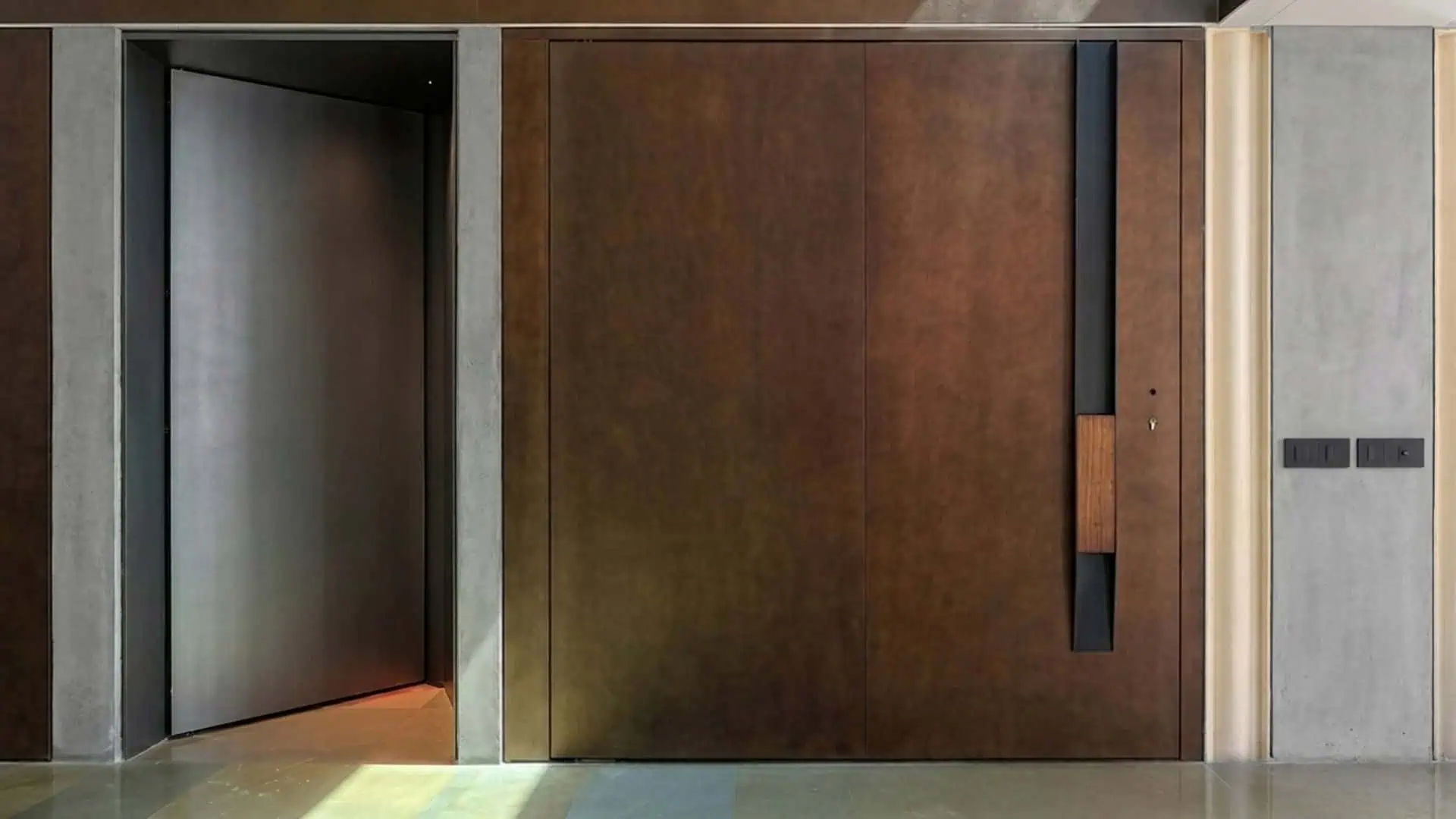 Main entrance door at Abyam House featuring a fully customized burnished bronze finish, a solid iroko wood pull handle, and an integrated Italian-engineered digital access system with multi-point locking by Silvelox, crafted by Metal Fabrik.