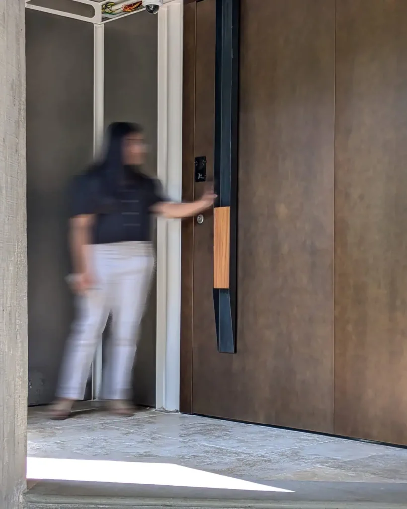 bespoke entrance door combining burnished bronze metalwork, iroko wood handle, and integrated smart access control with multi-point locking by Silvelox, fabricated by Metal Fabrik