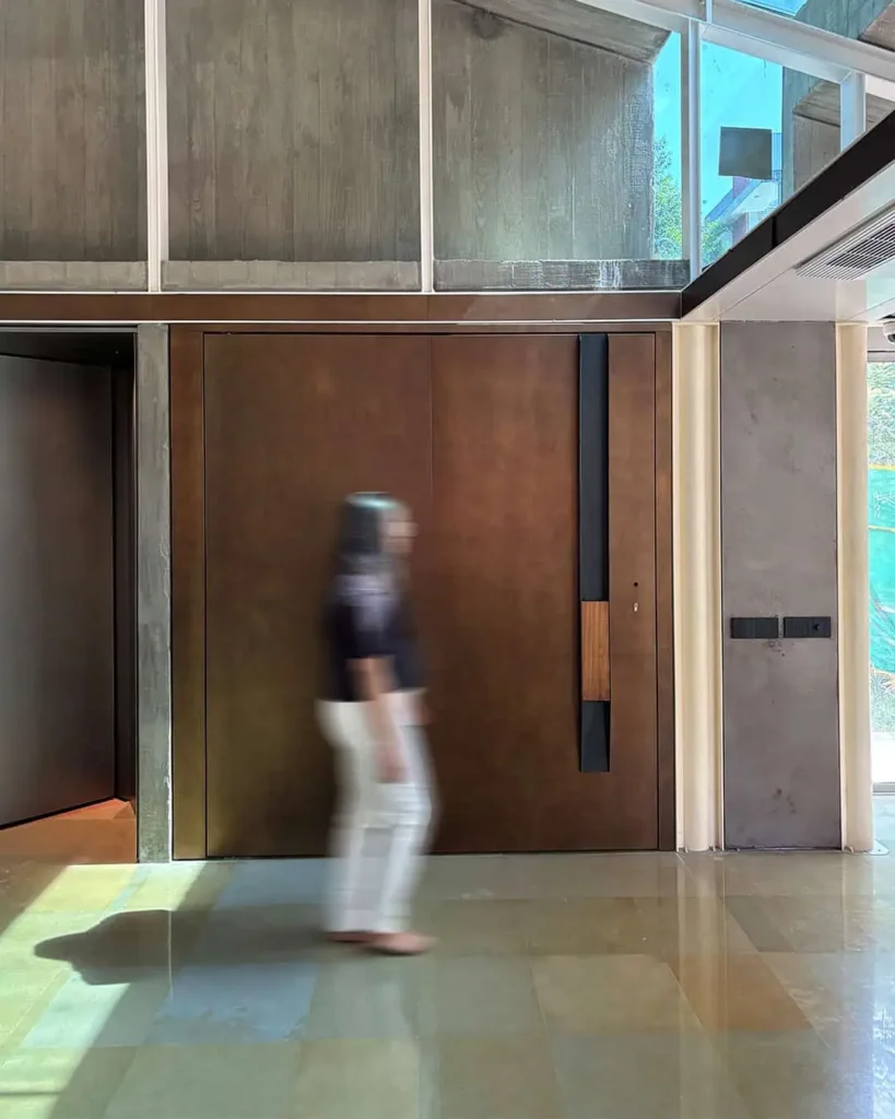 Architectural entrance door at Abyam House with custom burnished bronze cladding, iroko wood handle detail, and Italian-engineered multi-point digital locking system by Silvelox, produced by Metal Fabrik