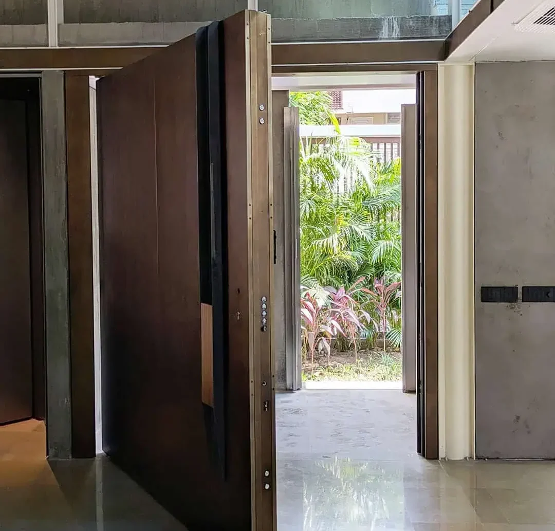 Main entry door showcasing a bespoke burnished bronze surface, solid iroko wood pull handle, and integrated digital locking technology from Silvelox, manufactured by Metal Fabrik.