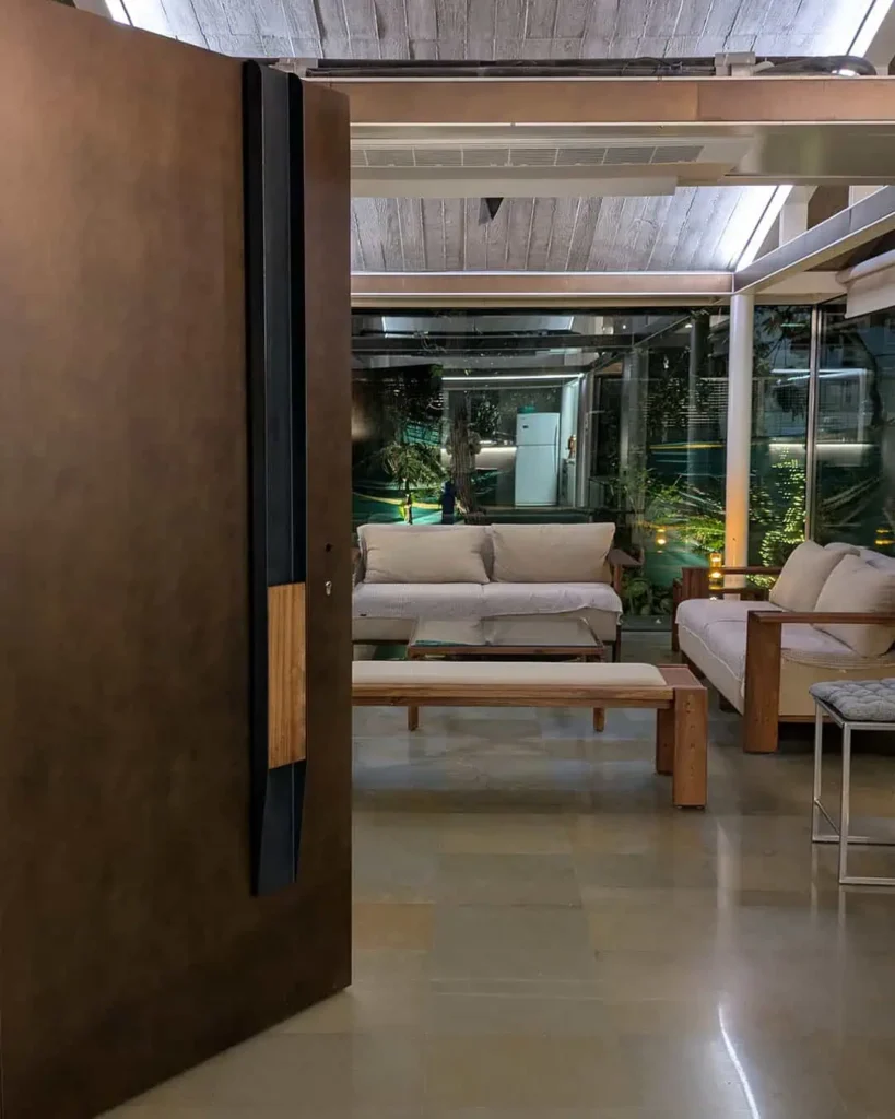 Luxury entrance door with a burnished bronze custom finish, paired with an iroko wood handle and advanced Italian smart access system with multi-point locking by Silvelox, crafted by Metal Fabrik.